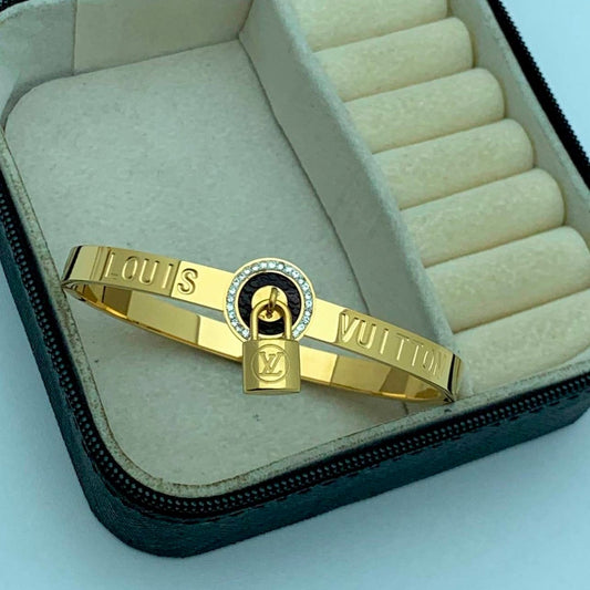 Gold bracelet with a lock design in an open jewelry box on a light blue background